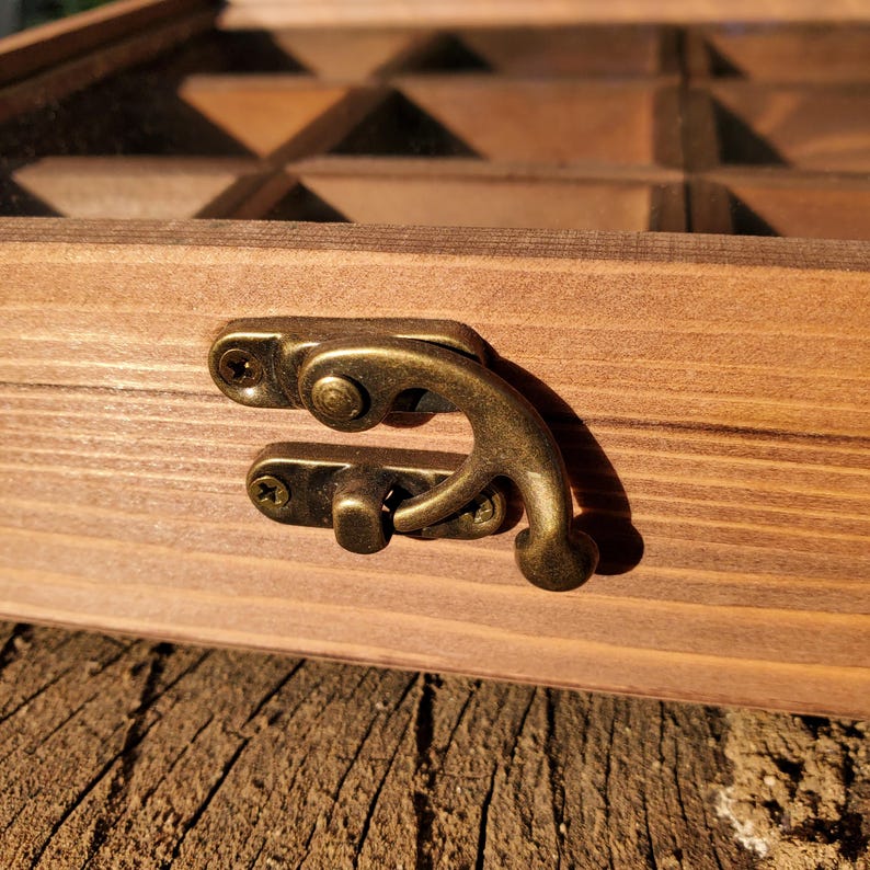 Op de afbeelding: Een houten doos met een scharnierend deksel en een messing sluiting. De doos heeft meerdere compartimenten en is gemaakt van donkerbruin hout.