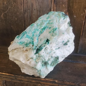 May include: A large, rough-hewn mineral specimen with a white base and striking turquoise and green inclusions. The stone has a crystalline structure and a natural, unpolished appearance, showcasing its raw beauty.