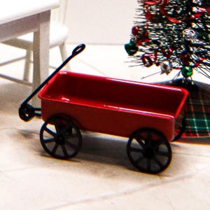 May include: A miniature red wagon with black wheels and a pull handle. The wagon is made of metal and has a glossy finish. The wagon is a decorative item, possibly for a holiday display.