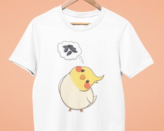Puede incluir: Camiseta blanca con una ilustración de dibujos animados de un cacatúa amarillo y blanco pensando en semillas de girasol.