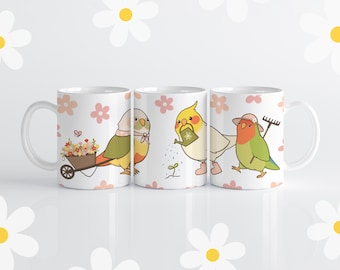Op de afbeelding: Drie witte keramische mokken met kleurrijke vogelillustraties. De mokken hebben een roze en wit bloemenpatroon. Eén mok toont een vogel met een kruiwagen vol bloemen, een andere toont een vogel die een plant water geeft, en de laatste mok toont een vogel met een hark.