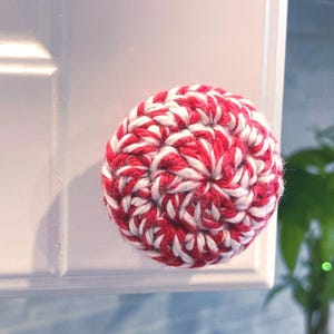 Puede incluir: Pomo de armario redondo, tejido a ganchillo en rojo y blanco, fijado a una puerta de armario blanca. El pomo presenta un patrón de ganchillo en espiral. Este pomo decorativo es adecuado para armarios de cocina o baño. Diámetro: aprox. 5 cm.