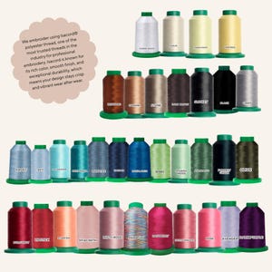 May include: A collection of Isacord polyester embroidery thread spools arranged in rows, featuring a wide spectrum of colors including white, yellow, brown, gray, blue, green, pink, and purple, each with a green base and a color label.