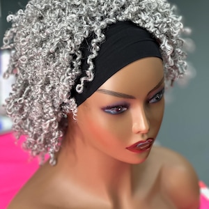 May include: A mannequin head with a gray curly wig and a black headband. The wig has a natural-looking texture and is styled in a short, voluminous cut. The mannequin has a neutral expression with red lipstick.