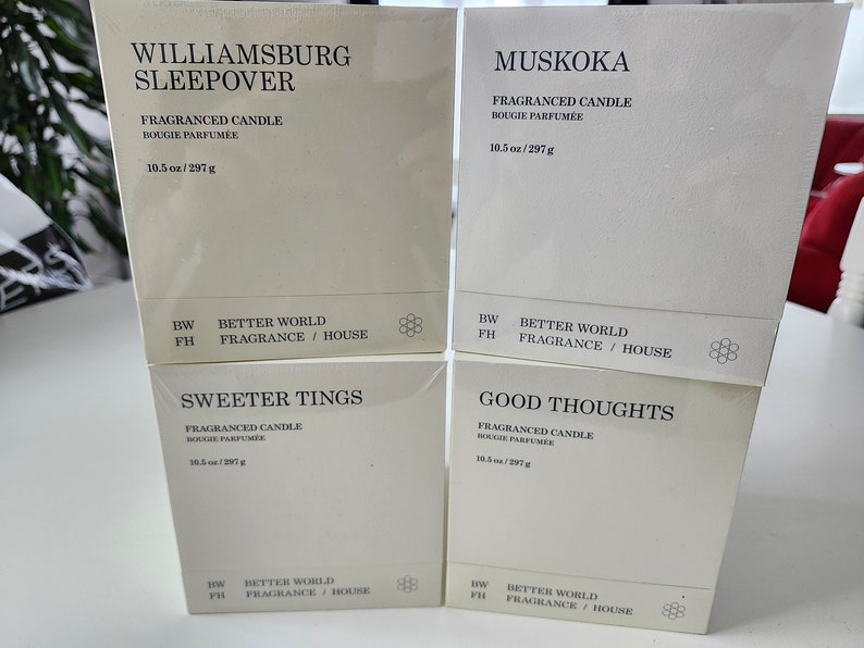 K&ouml;nnte beinhalten: Vier wei&szlig;e Boxen, die &uuml;bereinander gestapelt sind. Jede Box hat einen anderen Namen, der auf der Vorderseite aufgedruckt ist: Williamsburg Sleepover, Muskoka, Sweeter Tings und Good Thoughts. Jede Box ist eine Duftkerze mit 10,5 Unzen (297 Gramm). Auf der Unterseite jeder Box ist der Text "Better World Fragrance / House" aufgedruckt.
