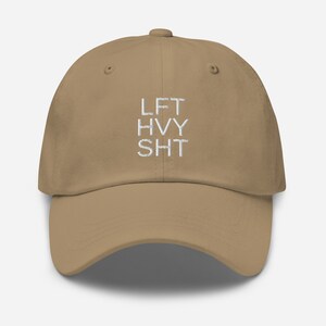 May include: A tan dad hat with white embroidered text that reads "LFT HVY SHT".