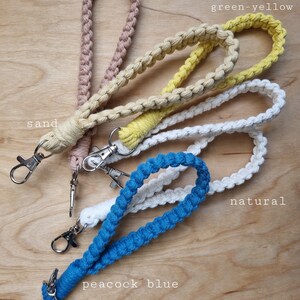 May include: Five different colored macrame keychains with metal clasps. The colors are latte, canary green-yellow, sand, natural, and peacock blue.