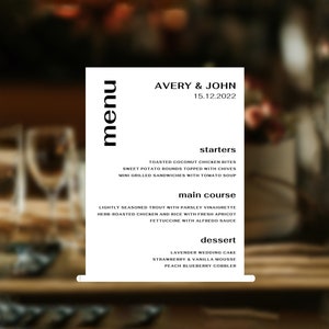 May include: A black and white menu with the names Avery & John and the date 15.12.2022. The menu lists starters, main course, and dessert options. The starters include toasted coconut chicken bites, sweet potato rounds topped with chives, and mini grilled sandwiches with tomato soup. The main course options are lightly seasoned trout with parsley vinaigrette, herb-roasted chicken and rice with fresh apricot, and fettuccine with Alfredo sauce. The dessert options are lavender wedding cake, strawberry & vanilla mousse, and peach blueberry cobbler.