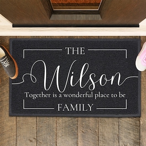 May include: Black doormat with white text that reads "The Wilson Family Together is a wonderful place to be".