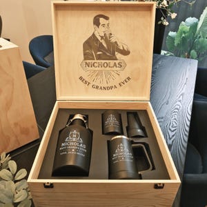 May include: A wooden gift box with a personalized inscription that reads "Nicholas Best Grandpa Ever". The box contains a black growler, a black tumbler, and a black mug, all with the same inscription.
