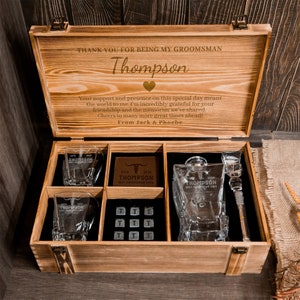 May include: Wooden box with a personalised message for a groomsman. The box contains two glasses, a bottle, a bottle stopper, and a small wooden plaque. The box is engraved with the name "Thompson" and the message "Thank you for being my groomsman".