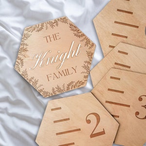 Könnte beinhalten: Wachstumstabelle aus Holz in sechseckiger Form mit floralem Design und dem Text "The Knight Family". Die Tabelle enthält einzelne sechseckige Teile mit den Zahlen 1, 2 und 3.