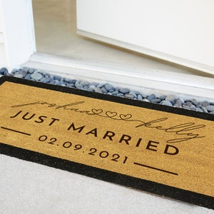 以下が含まれることがあります： 黒い縁取りのある茶色のココナッツ繊維のドアマットで、"Just Married"という文字と、"Sophia"と"Kelly"という名前、そして"02.09.2021"という日付が黒で書かれています。