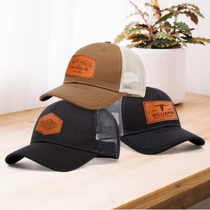May include: Three baseball caps in brown, black and grey with leather patches. The patches have different text on them, including "Best Man", "Nicholas", "Williams", and "Vladislav".