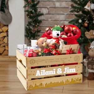 May include: A wooden crate with a red Santa sack filled with Christmas decorations, stuffed toys, and wrapped presents. The crate is personalised with the text "Delivering the magic of Christmas to Ailani & Jim".