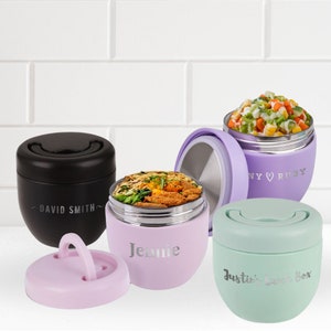 May include: Four insulated lunch containers with personalised names. The containers are in various colours, including black, purple, and green. The containers have a stainless steel interior and a lid with a handle.
