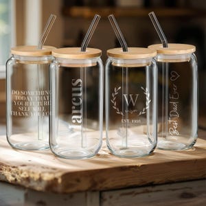 May include: Four glass drinking jars with bamboo lids and straws. The jars are engraved with different personalised messages: "Do something today that your future self will thank you for", "Marcus", "W alison EST. 1991", and "Best Dad Ever".