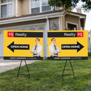 Może przedstawiać: Dwa żółto-czarne szyldy nieruchomości z napisem "HJ Realty" i "Open Home" ze strzałką. Znaki mają zdjęcie mężczyzny i są wyświetlane na zielonym trawniku.