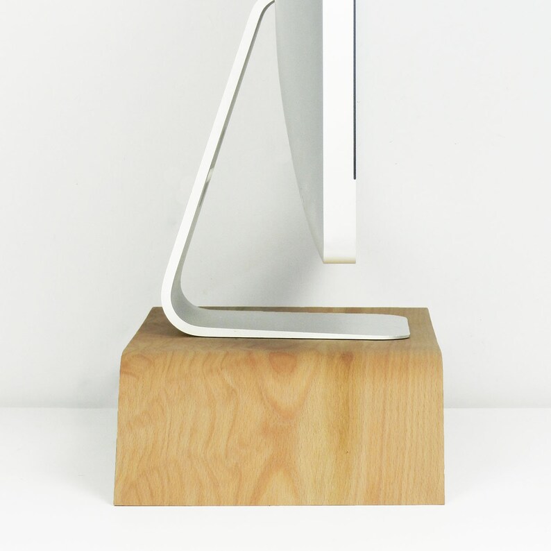 May include: A white computer monitor with a curved stand sits on a wooden riser. The riser is made of light brown wood with a natural grain pattern.