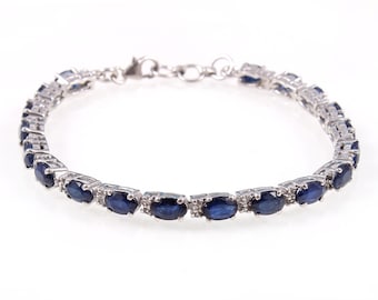 May include: A silver tennis bracelet with oval-shaped blue sapphires and small clear diamonds.