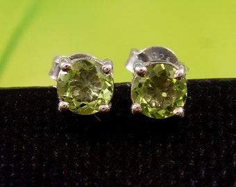 Könnte beinhalten: Ein Paar silberne Ohrstecker mit grünen Peridot-Edelsteinen. Die Ohrringe sind in einem schlichten, klassischen Stil gehalten.