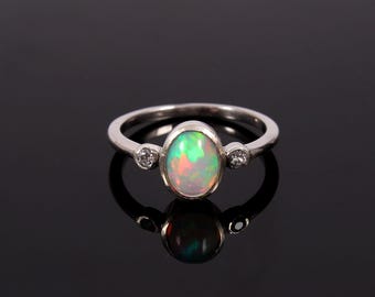 May include: A silver ring with a large oval opal gemstone and two smaller round diamonds on either side.