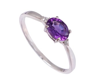 May include: A silver ring with a large oval amethyst gemstone and two smaller diamond accents.