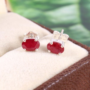 Puede incluir: Un par de pendientes de plata con piedras de rubí rojo ovaladas.