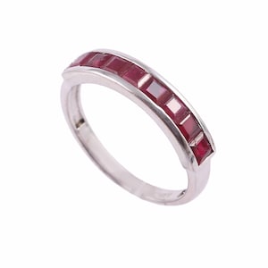 May include: A silver band ring with a row of red square-shaped gemstones.