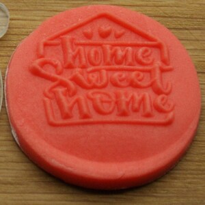 May include: Red silicone stamp with the words "Home Sweet Home" in a house shape.