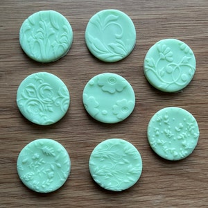 May include: Eight round, light green, silicone cake decorating stamps with various floral designs.