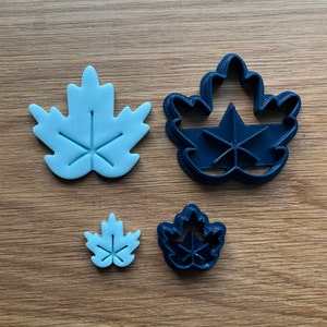 May include: Three different sized cookie cutters in the shape of a maple leaf. The largest cutter is light blue, the medium cutter is dark blue, and the smallest cutter is light blue.