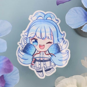 Könnte beinhalten: Ein gestanzter Aufkleber mit einer Cartoonfigur mit hellblauen Haaren und passendem Outfit. Die Figur zwinkert und lächelt, mit einem Mikrofon-Design an den Seiten. Der Aufkleber hat einen weißen Rand und ist vor einem hellblauen Hintergrund platziert.