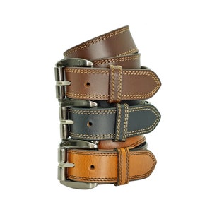 May include: Three leather belts stacked on top of each other. The top belt is brown, the middle belt is black, and the bottom belt is tan. All three belts have a silver buckle and are stitched with a contrasting thread.