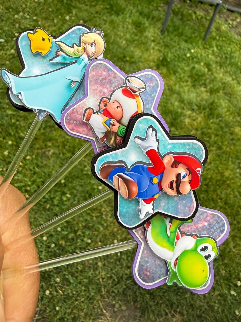 Puede incluir: Un conjunto de cuatro adornos decorativos con los personajes de Nintendo Rosalina, Toad, Mario y Yoshi. Cada personaje est&aacute; montado sobre un recorte en forma de estrella con acabado hologr&aacute;fico, unido a un palito de pl&aacute;stico transparente.