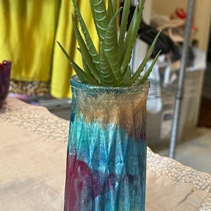 May include: A small, colorful, textured glass vase with a gold rim, holding a green succulent plant.