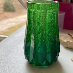 May include: A green glass vase with a faceted design and glitter embedded in the glass.