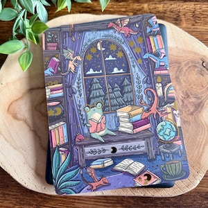 Può includere: Illustrazione colorata di una scena di biblioteca con una rana che legge un libro. Sono presenti draghi, libri e un mappamondo. Lo sfondo mostra una finestra con un cielo notturno e alberi.