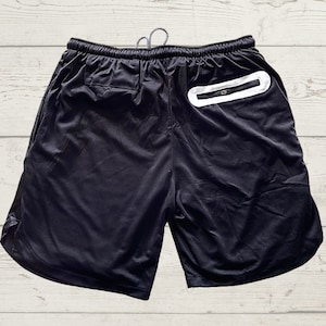May include: Black athletic shorts with a white zippered pocket on the back.