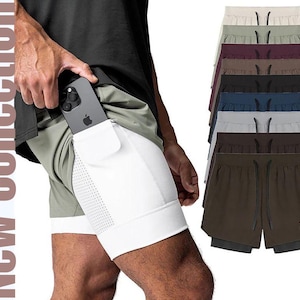 Puede incluir: Pantalones cortos deportivos con bolsillo para teléfono incorporado, mostrados en varios colores, incluyendo verde oliva, marrón y azul marino. Los pantalones cortos tienen una capa exterior blanca con un diseño perforado. El texto "New Collection" es visible.