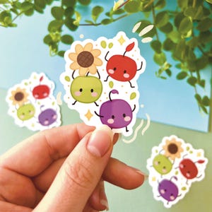 Könnte beinhalten: Ein farbenfroher Aufkleber mit Cartoon-Früchten und einer Sonnenblume. Der Aufkleber zeigt eine rote Kirsche, eine grüne Olive und eine lila Pflaume, jeweils mit lächelnden Gesichtern und kleinen Gliedmaßen. Die Sonnenblume ist gelb und braun.