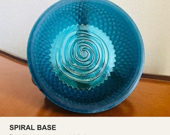 May include: A circular, translucent teal shaving bowl featuring a textured diamond pattern on the outer walls and a raised spiral design on the interior base. The text SPIRAL BASE and The visible interior texture supports lathering are printed below.