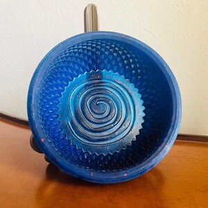 The royal blue sparkle resin shaving bowl seen square on, the raised spiral coil in the floor ringed by a sawtooth edge and a moulded diamond lattice running up the wall.