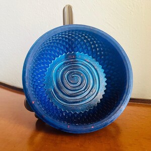 Royal blue sparkle resin shaving bowl standing upright on dark wood against a pale wall, the raised spiral coil visible in the floor and a moulded diamond lattice running around the wall.