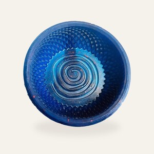 Royal blue sparkle shaving bowl on a warm off-white background, standing upright so the raised spiral coil in the floor and the moulded diamond wall are both visible.