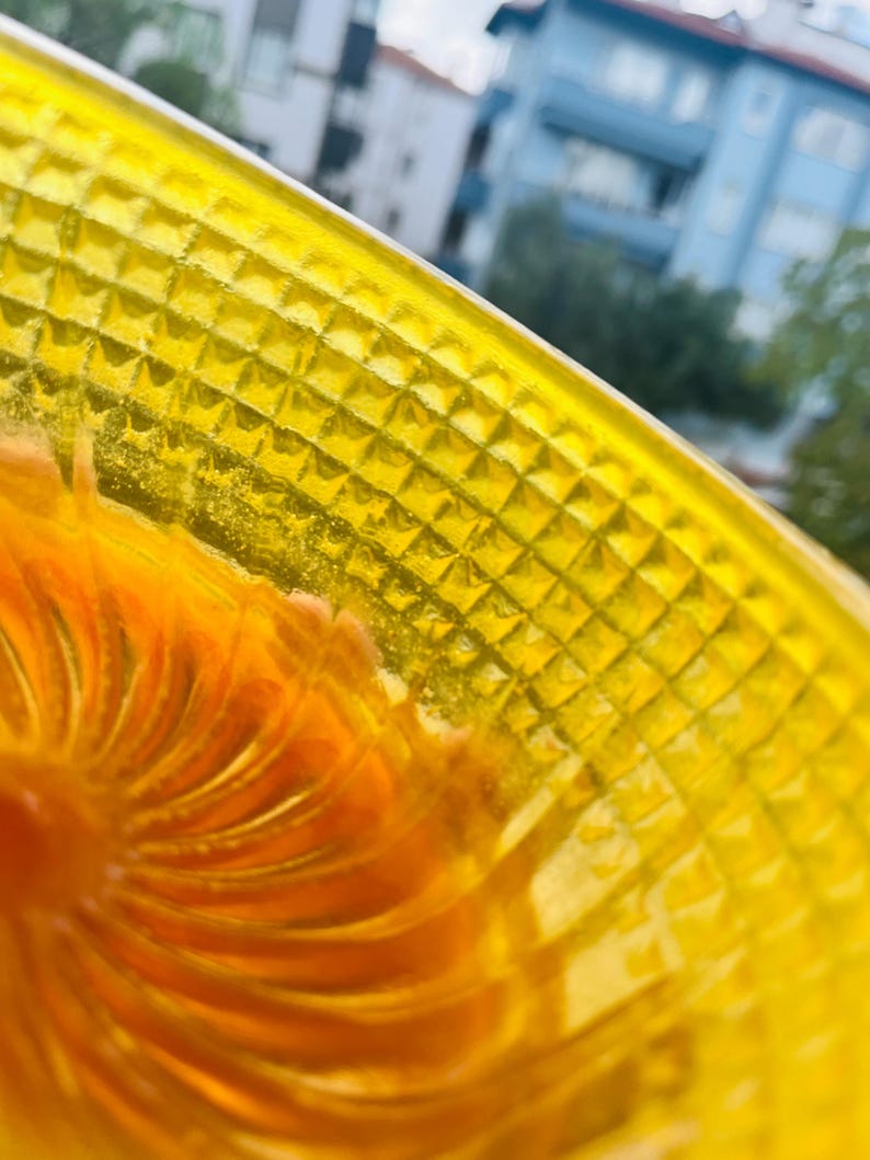 Close up of the yellow shaving bowl wall in daylight, showing the pyramid cut texture in cast resin and the orange fan swirl inside the lather well.