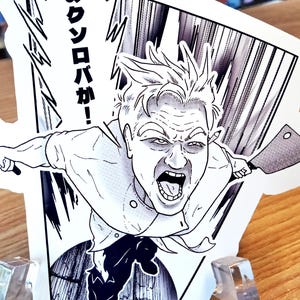 May include: A white sticker with a black and white illustration of a chef in a dynamic pose, yelling and holding two knives. The sticker includes Japanese text in a speech bubble. The image has a comic book style.
