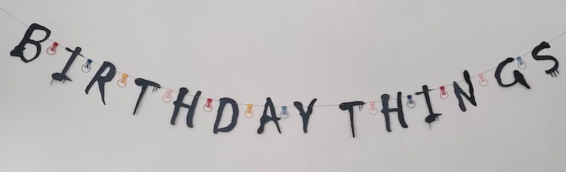 May include: Black and white banner with the words "BIRTHDAY THINGS" strung together with colorful lightbulbs.