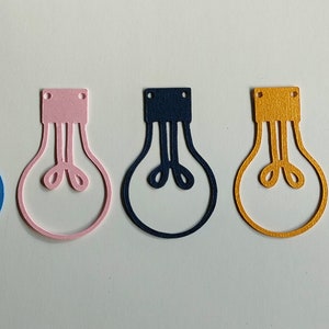 May include: Six lightbulb shaped cutouts in different colors: blue, pink, navy blue, yellow, and red. The cutouts are made of felt and have a simple design.