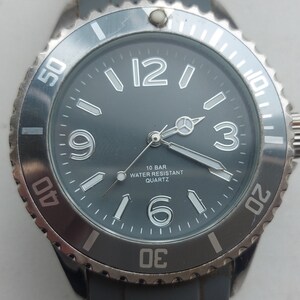 May include: A black and silver wristwatch with a black face and white numbers. The watch has a silver bezel with white markings and a black rubber band.